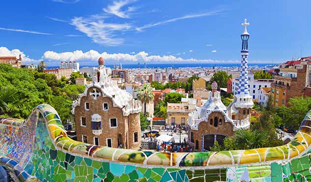 Parc Guell, Barcelona, Spain. Main entrance to Gaudi's Parc Guell and skyline of Barcelona.